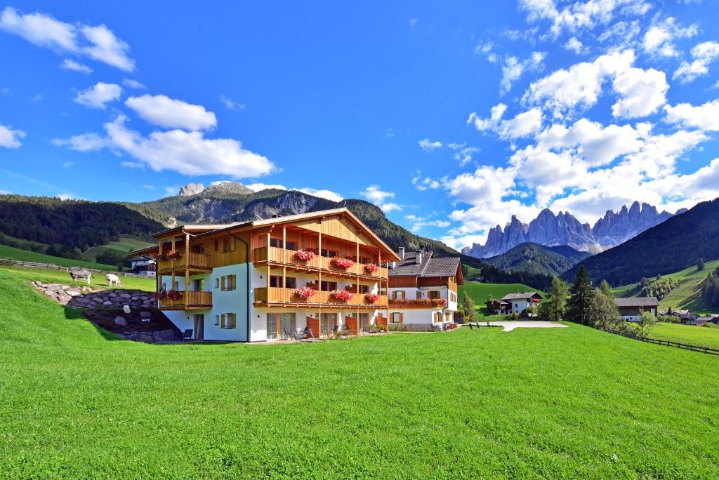 un bâtiment dans un champ avec des montagnes en arrière-plan dans l'établissement Proihof, à Funes