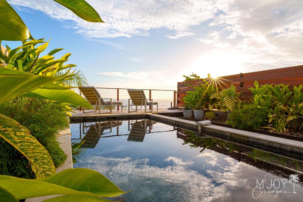 a pool of water with chairs and plants at VILLA ESCALE TROPICALE - classée 5 in Petite Île