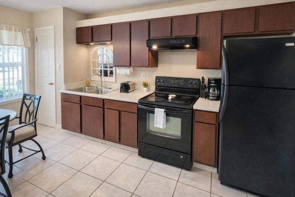 a kitchen with a black refrigerator and a sink at Great Pool - Beach Access - Small Family Perfect in South Padre Island