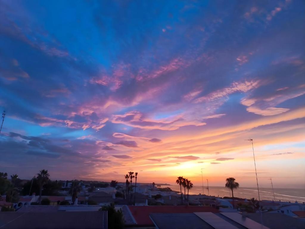 a sunset over a city with palm trees and the ocean at Luca's House - Villa sul mare con piscina in Giovinazzo