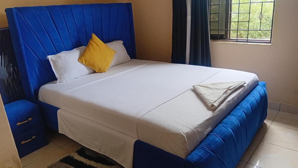 a bedroom with a large bed with a blue headboard at Breezes home Bamburi in Bamburi