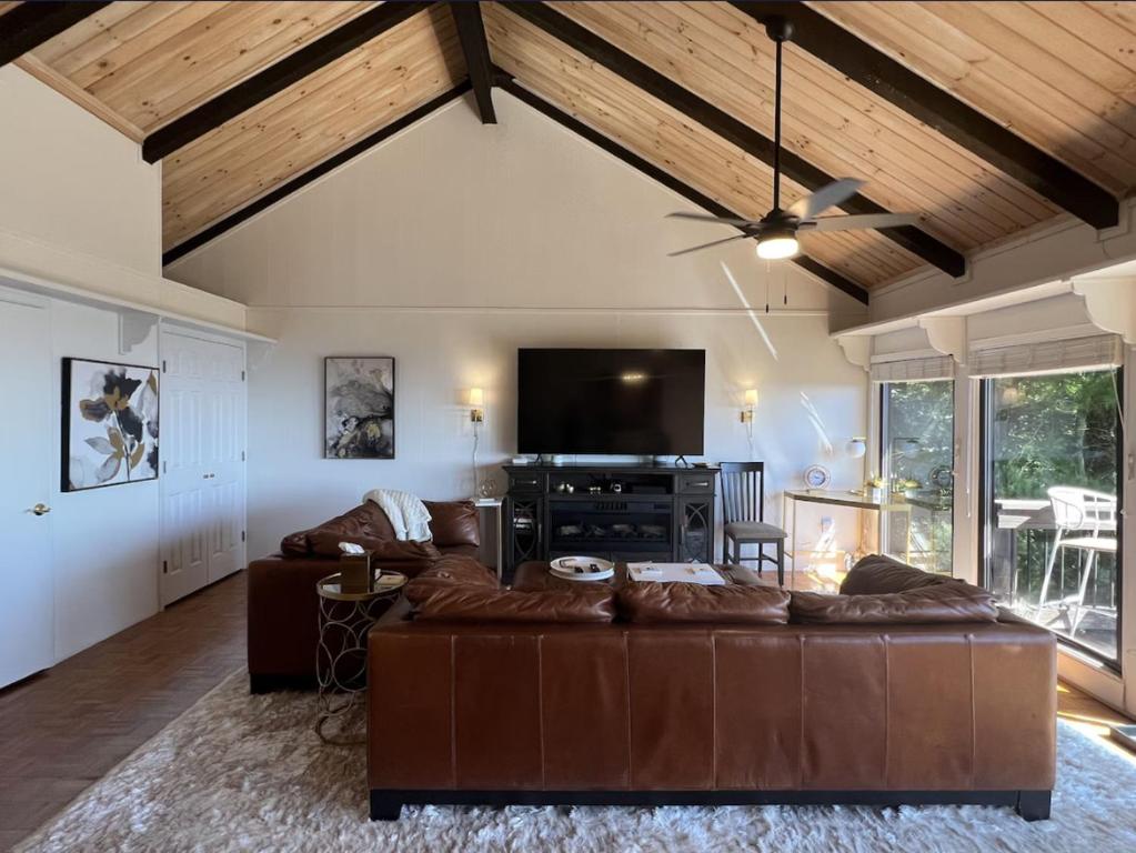 a living room with a brown couch and a flat screen tv at Remarkable Mountain Escape! Breathtaking Views & Pet Friendly! in Hillsville