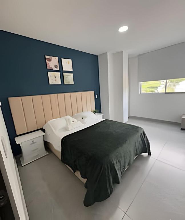 a bedroom with a large bed and a blue wall at alojamientos la martina in Cali