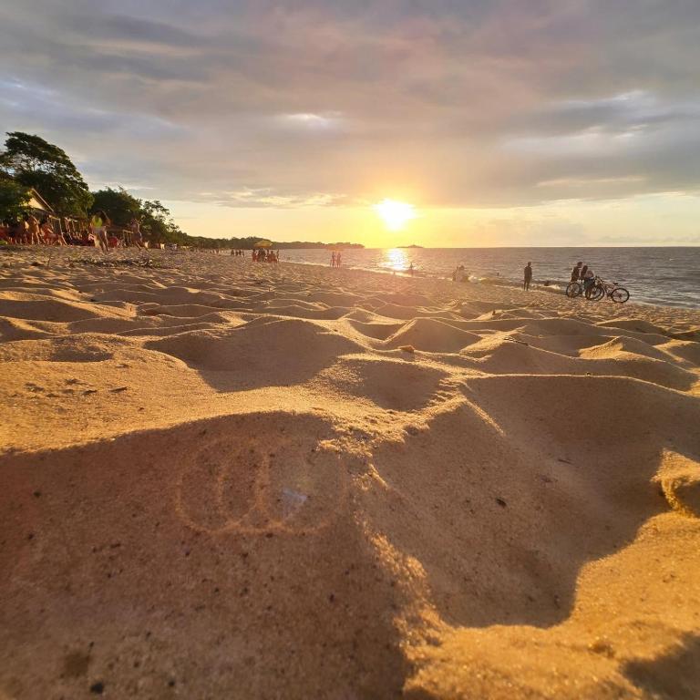 a beach with a sunset and people riding bikes at Pousada O Povorello - a 1 minuto a pé da Praia Grande da Baía do Sol in Mosqueiro