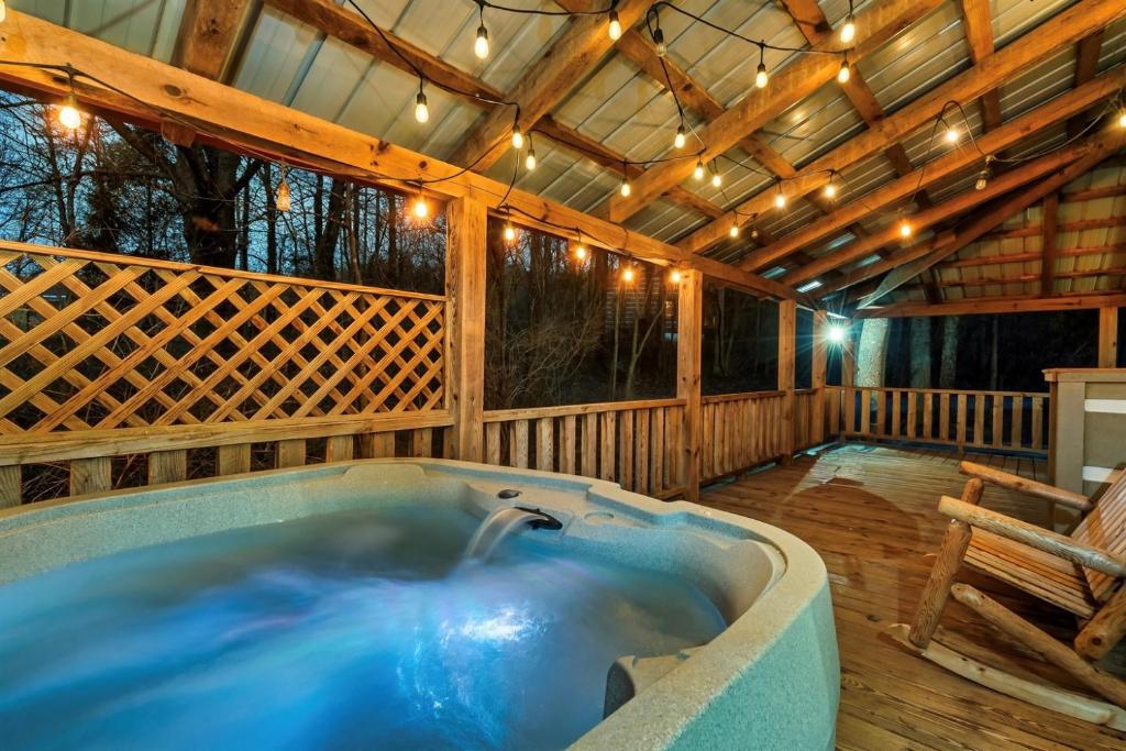 a hot tub on a deck with a wooden ceiling at Smokies Log Cabin Hot Tub, Fire Pit & Arcade in Townsend