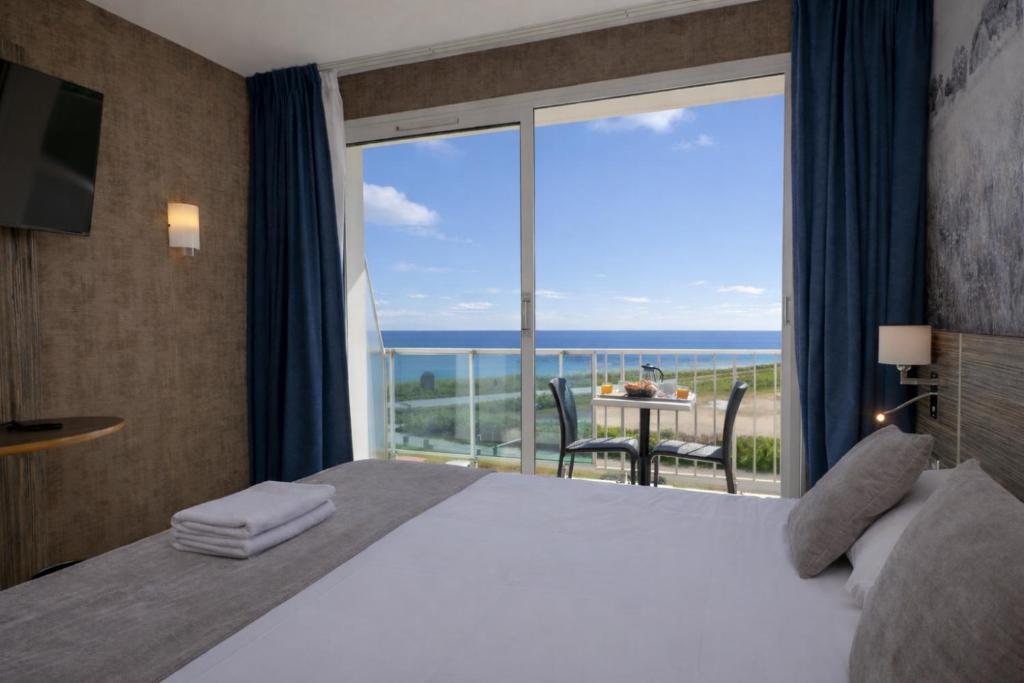 a bedroom with a bed and a large window at Hotel Europa in Quiberon