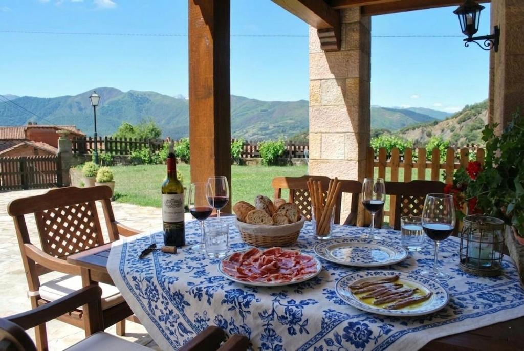 a table with plates of food and wine glasses at Apart con piscina Lebanes Picos de Europa in Torices