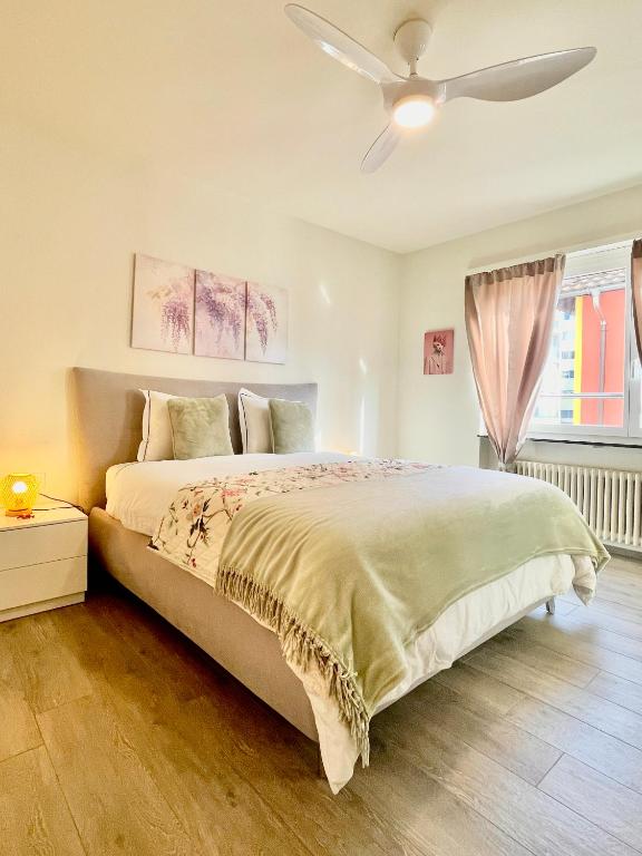 a bedroom with a large bed with a ceiling fan at RELAX Glicine Apartment in Locarno