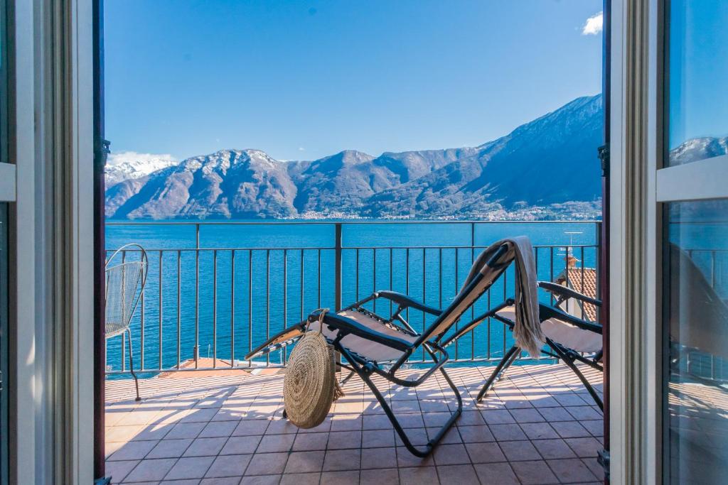 a chair on a balcony with a view of the water at Alba on Lake Como by Rent All Como in Sala Comacina