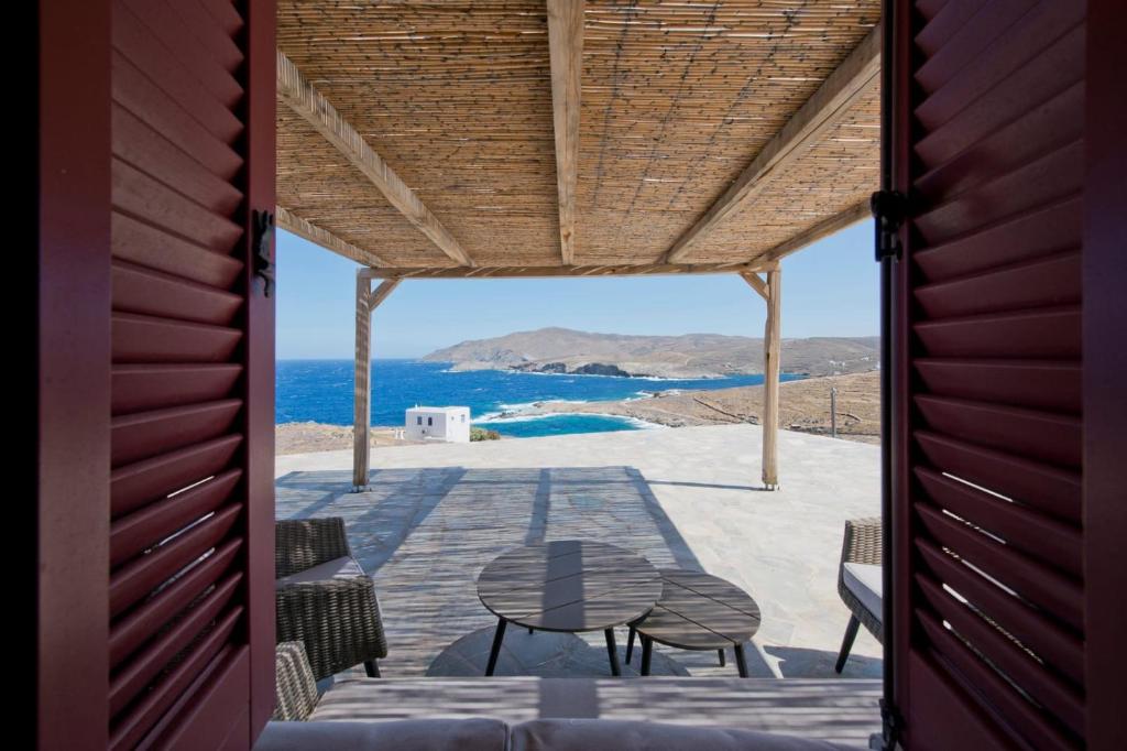 a patio with a table and chairs and the ocean at Stone Wave Kythnos in Loutra