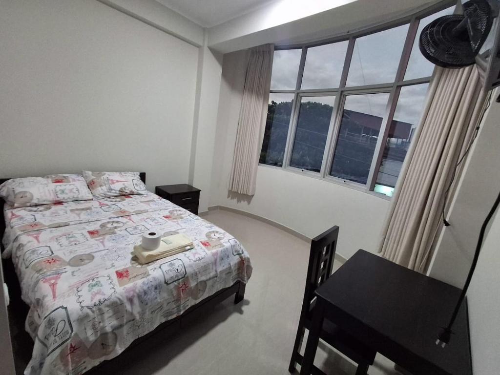 a bedroom with a bed and a desk and a window at Hospedaje Jasmine in Tarapoto
