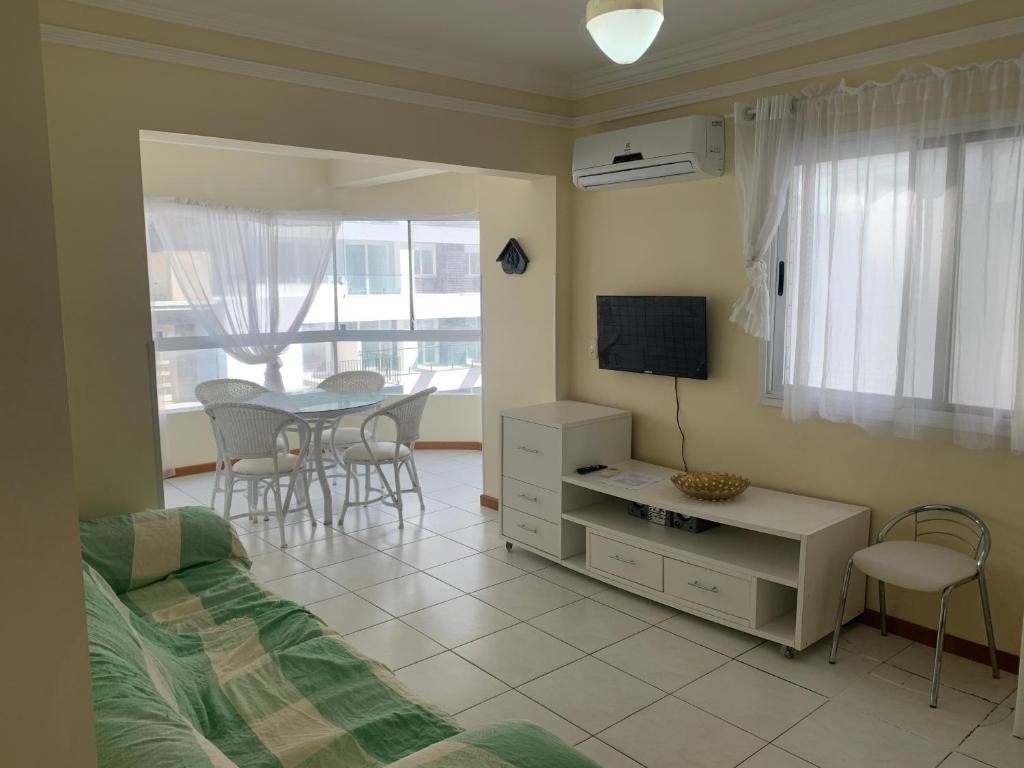 a bedroom with a bed and a table and a tv at Apartamento junto mar, bem ventilado e iluminado - Antilhas 679 in Capão da Canoa