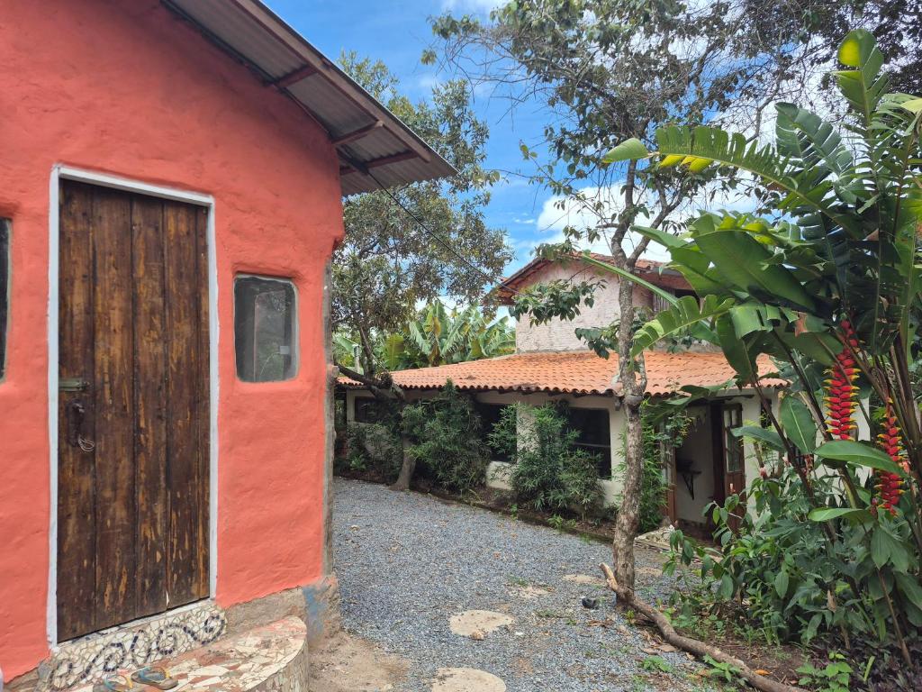 a red house with a door and a tree at Bela Oyá Casa Hostel in Vale do Capao