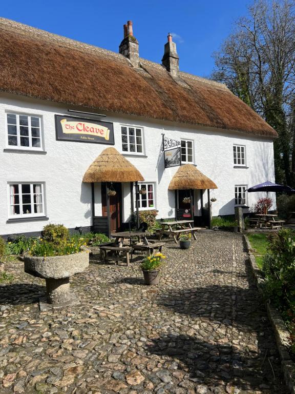 a white building with tables and benches in front of it at The Cleave Inn in Lustleigh