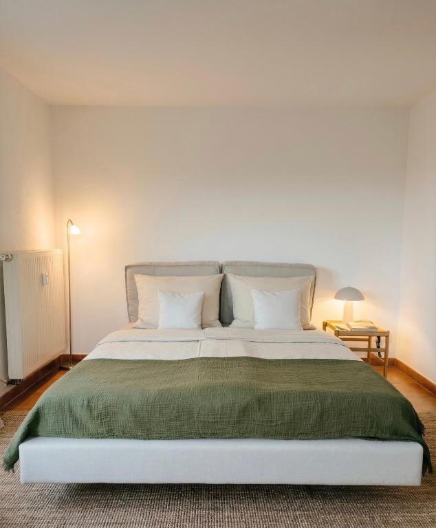 a bedroom with a large bed with a green blanket at Modernes Studio mit Balkon & Seeblick am Biggesee in Olpe