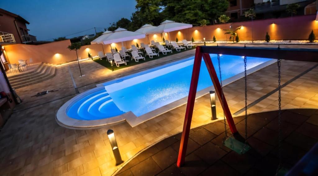a swimming pool at night with tables and chairs at Sobe Biser Dunava - smještaj uz Dunav in Vukovar