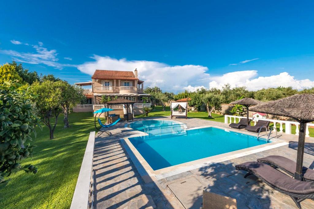 a swimming pool in a yard with a house at Maxim in Corfu