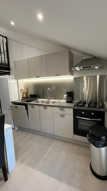 a kitchen with white cabinets and a stove top oven at Le loft sous les toits in Arles