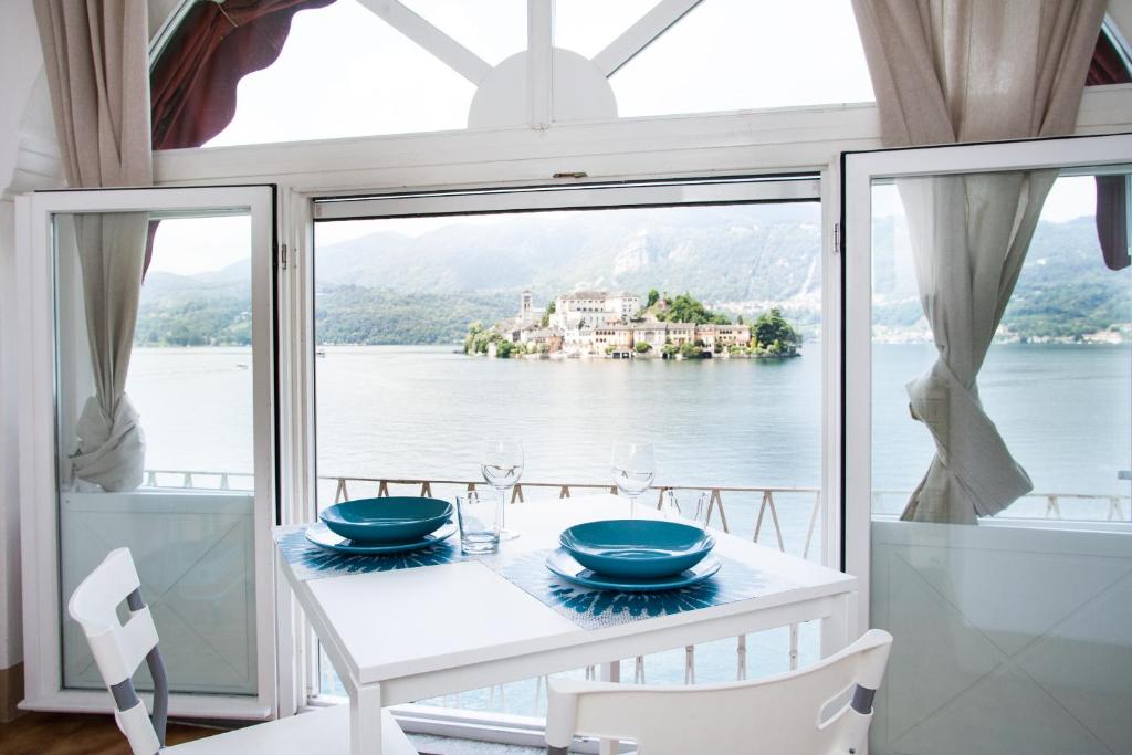 een eetkamer met uitzicht op het water bij -Ortaflats- Appartamento Gli Archi in Orta San Giulio
