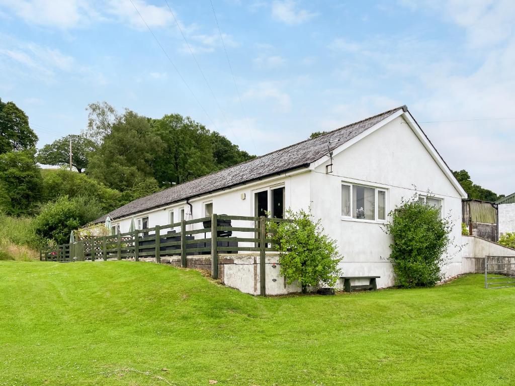 a white house with a fence and green grass at Uk47550 - Cairnsmore Cottage in Newton Stewart