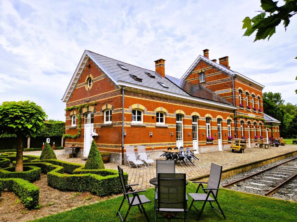 a large brick building with chairs in front of it at Station Racour 'Magasin de la gare' in Landen