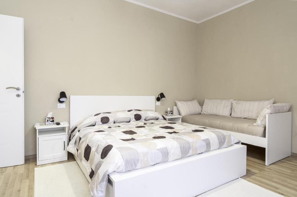 a white bedroom with a bed and a couch at Dimora Stadio Biella in Biella
