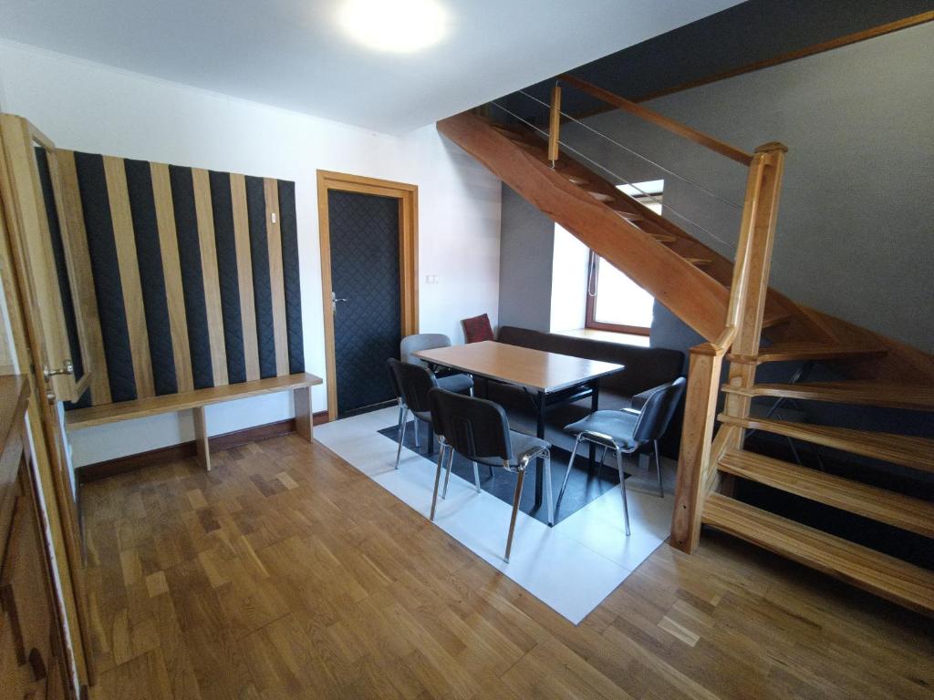 a dining room with a table and chairs and a staircase at Spichlerz Apartmanety in Strzeskowice Duże