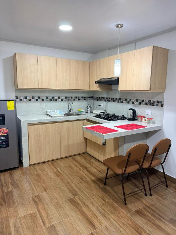 a kitchen with a counter and two chairs and a refrigerator at Mini centrica suite privada con todo incluido in Loja