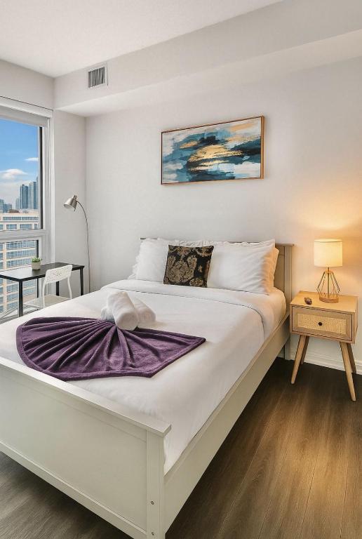 a bedroom with a large white bed and a window at Cozy Room & Bath Downtown Toronto in Toronto