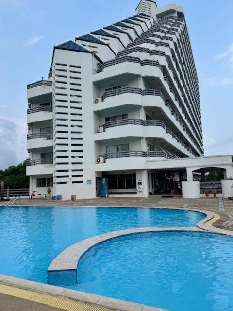 a large building with a swimming pool in front of a building at Tree Top Beach Condo in Ban Pak Khlong Phe