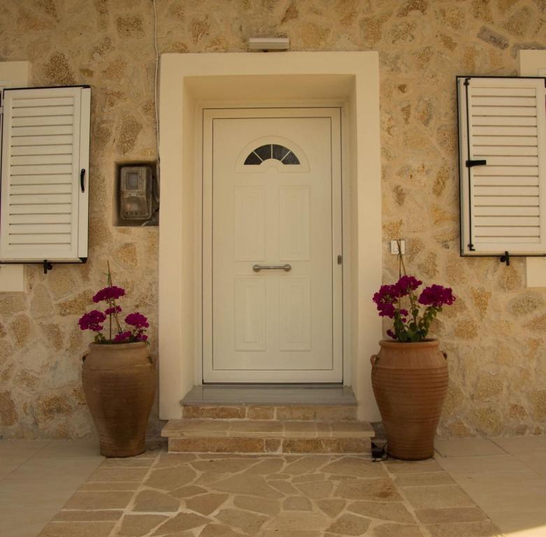 a white door and two vases with flowers at Villa Aristidis Strates in Argyrádes