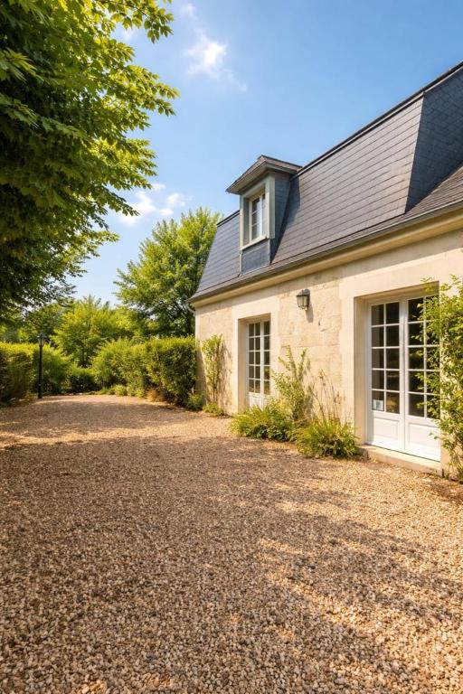 a house with a gravel driveway in front of it at La maison aux 5 nids in Saint-Cyr-sur-Loire