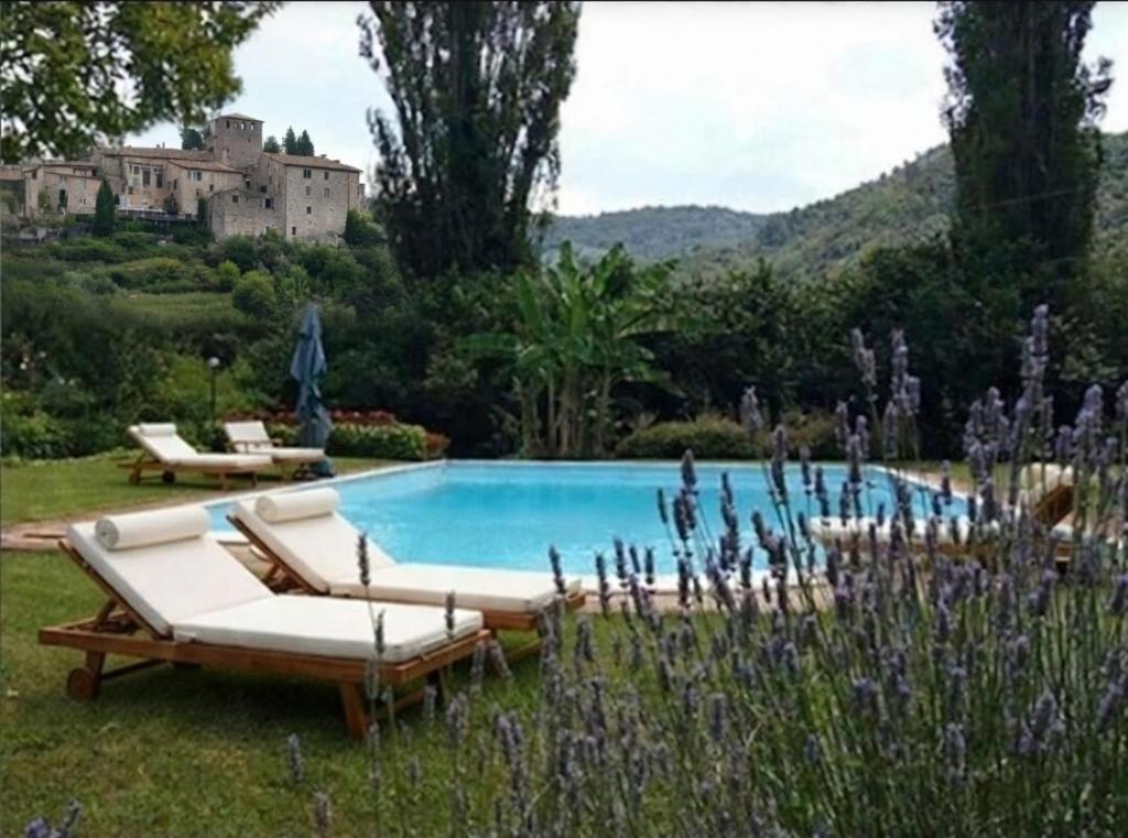 a pool with lounge chairs and a house in the background at La chiave del Tempo in Casteldilago