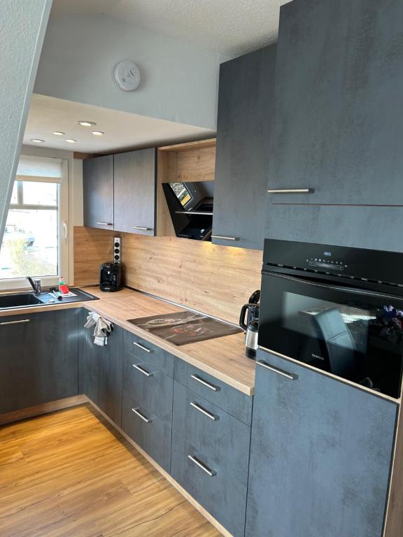 a kitchen with gray cabinets and a black appliance at Haus Pop in Borkum