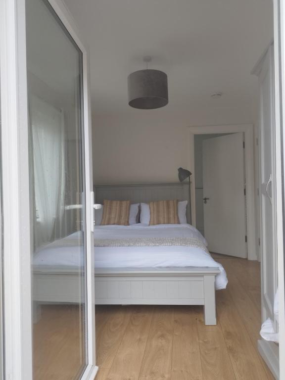 a bedroom with a white bed and a mirror at Knightstown Apartment in Valentia Island