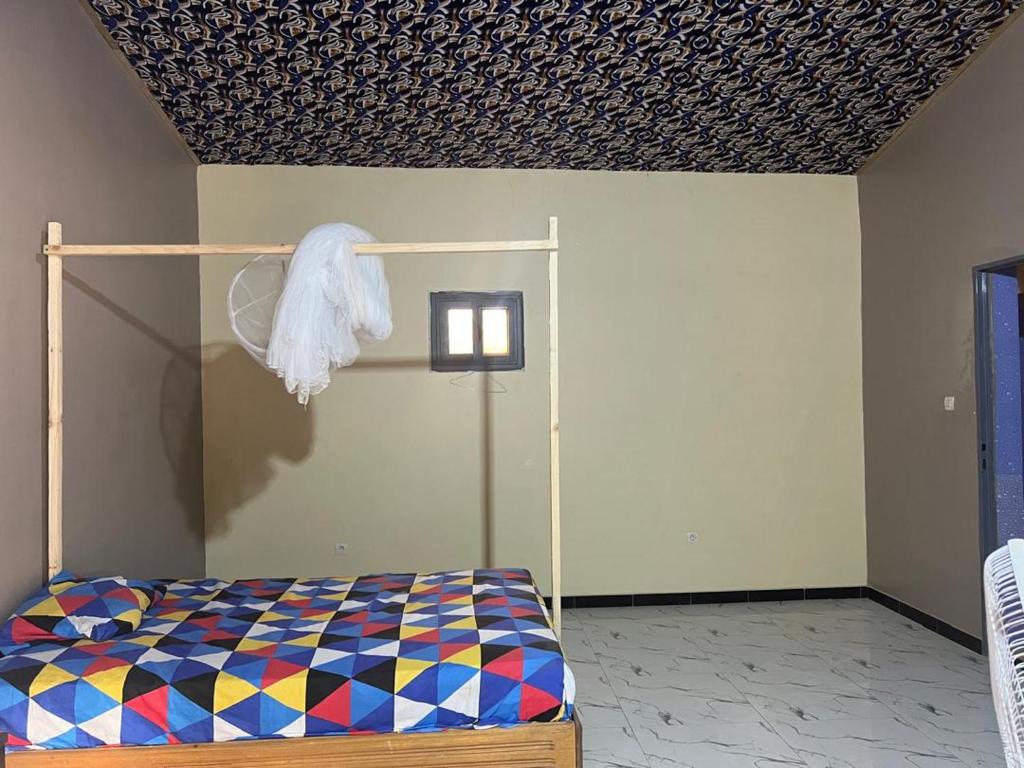 a bedroom with a bed and a ceiling at Chez Aicha Ndangane in Ndangane