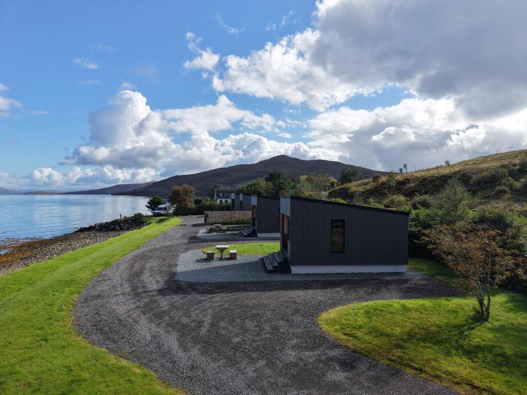 a small house on a gravel road next to the water at Angusfield Cabins in Sconser