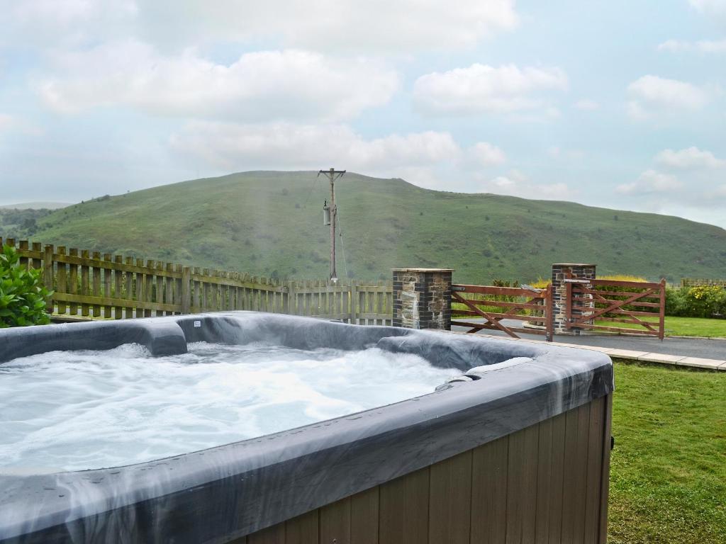 a hot tub with a mountain in the background at Eithinog in Talybont