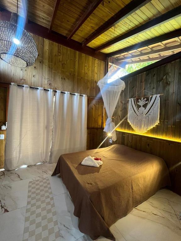 a bedroom with a bed in a wooden room at Jeribucaçu bangalô in Itacaré