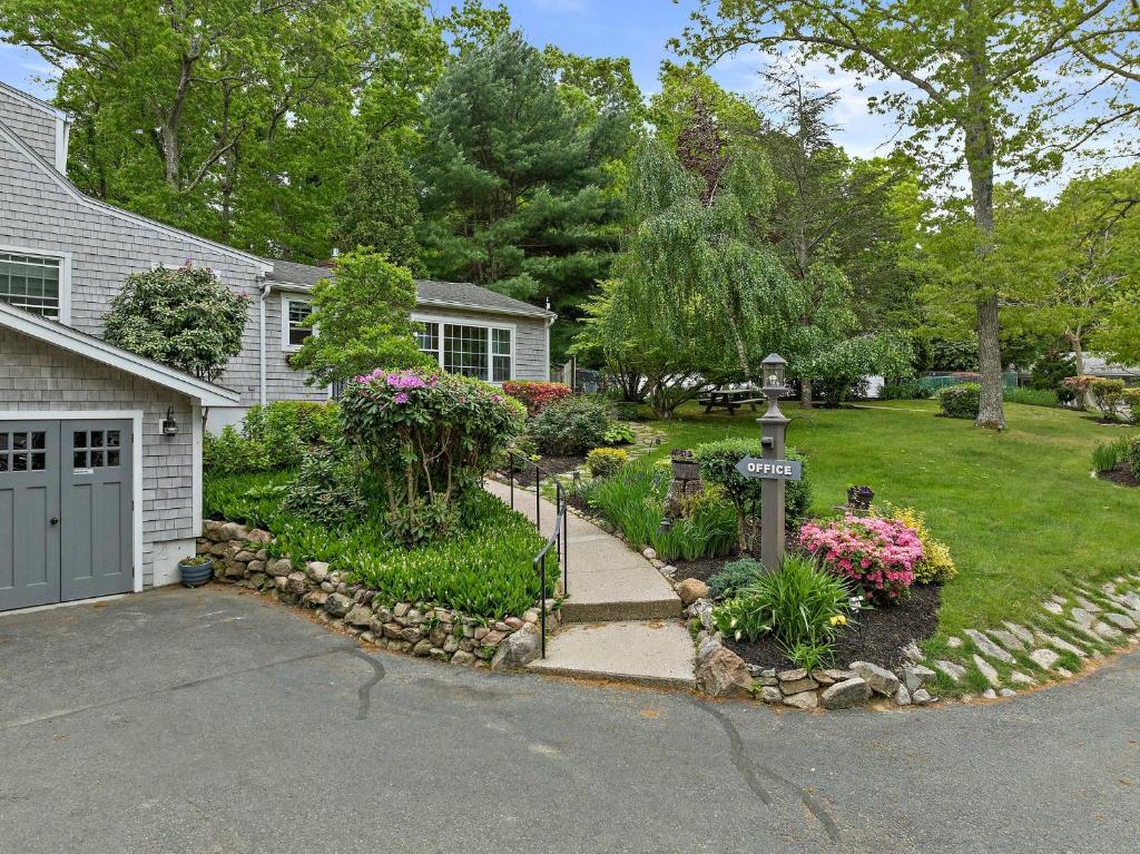 a house with a garden with flowers and a driveway at Sandwich Inn and Suites in Sandwich
