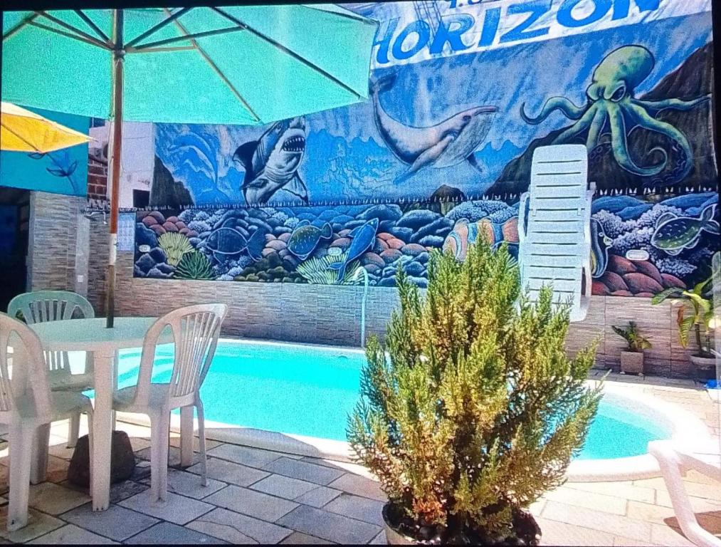 a pool with a table and an umbrella and a mural at Pousada Inn Blue Horizon in Porto De Galinhas