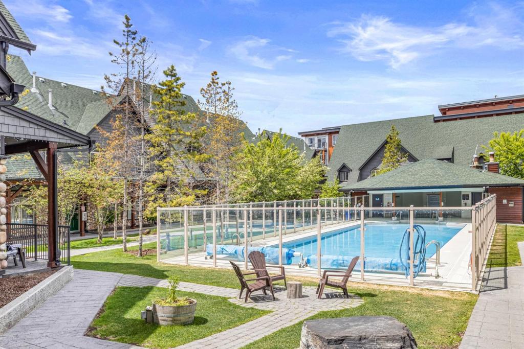 a swimming pool in a yard with chairs next to a house at Mystic Chalet- Views, Pool, Hot Tub, Pets - managed by Little Sister Getaways in Canmore