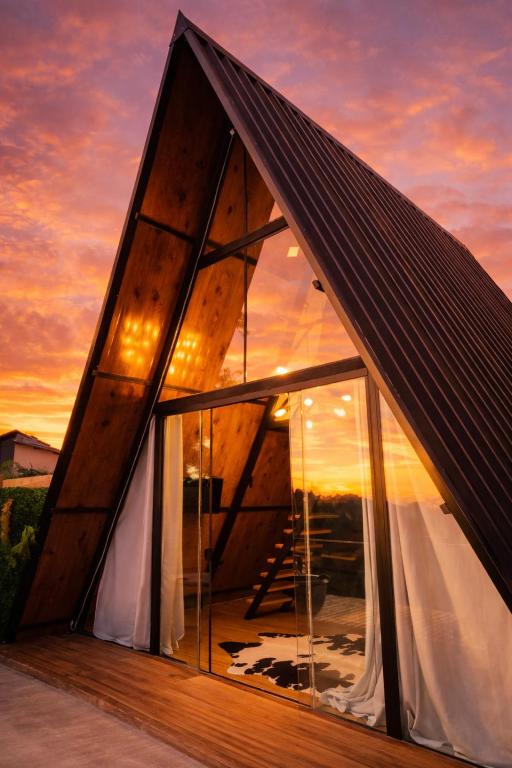 a frame house with a large window at sunset at Cabana do sol Chalés Vero Verde in Serra Negra
