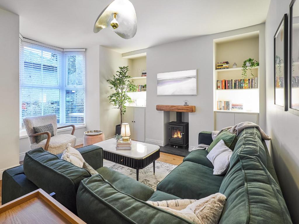 a living room with a green couch and a fireplace at Hovera Cottage in Windermere