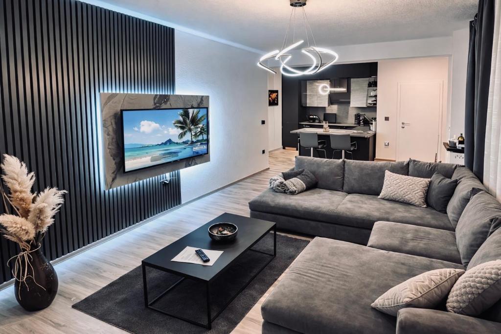 a living room with a couch and a tv on a wall at Guest House Eden in Bihać