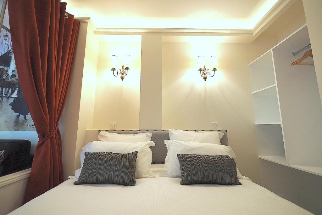 une chambre avec un lit avec des oreillers blancs dans l'établissement Louvre Opera Classic ChicSuites, à Paris