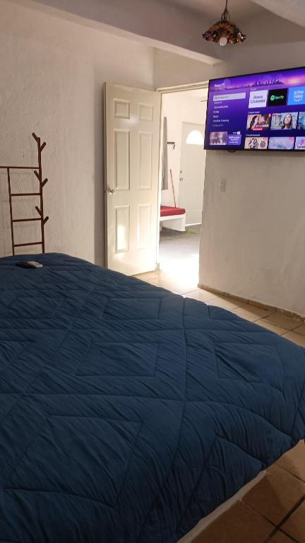 a bedroom with a blue bed and a large screen at Bungalow Josefina flores in Lo de Marcos
