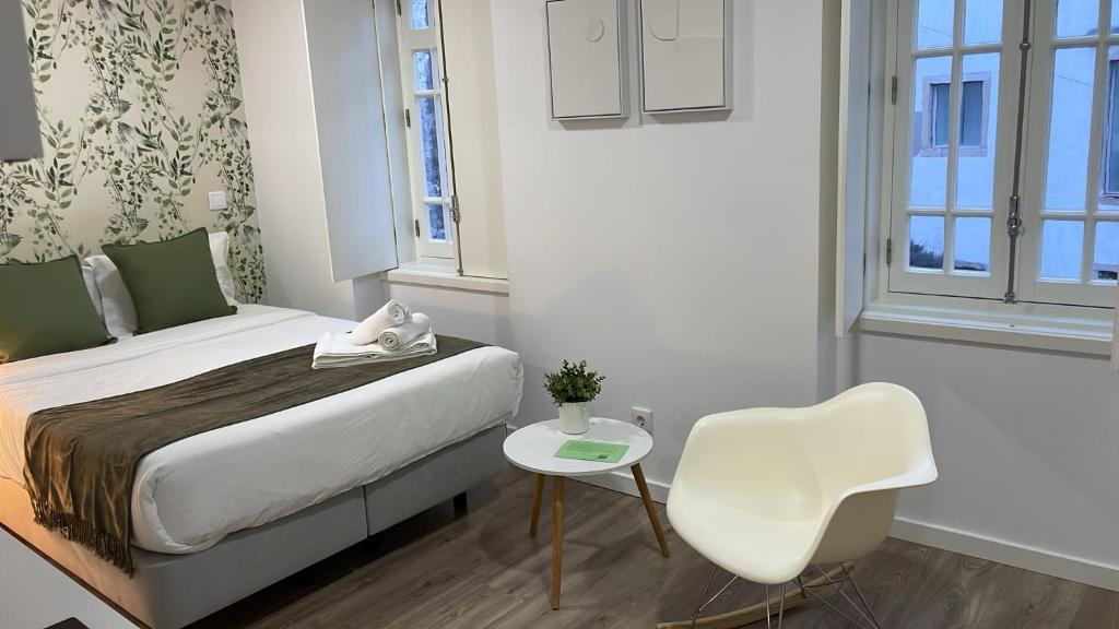 a small room with a bed and a white chair at Jardim da Trindade in Coimbra