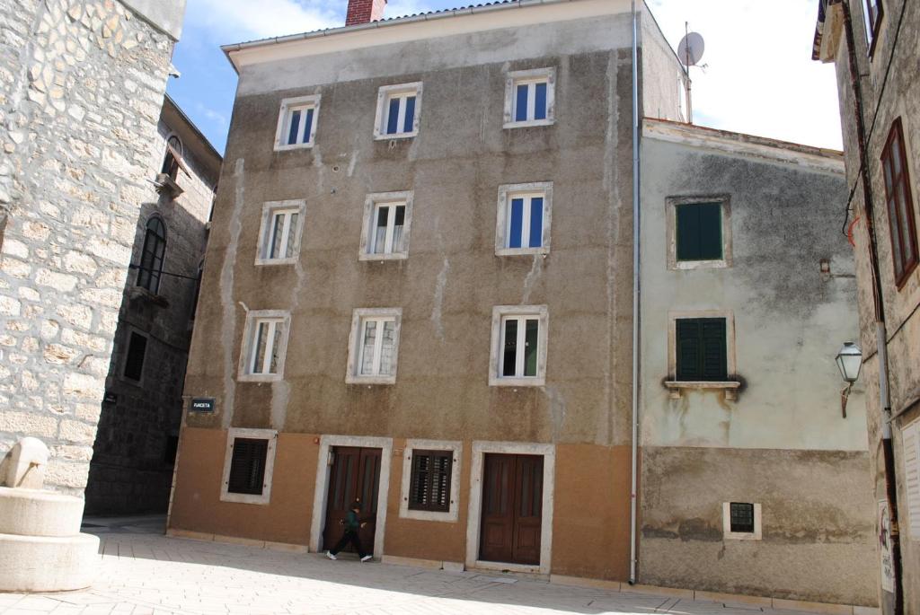 an old building with white windows in an alley at Rooms Piazzetta in Cres