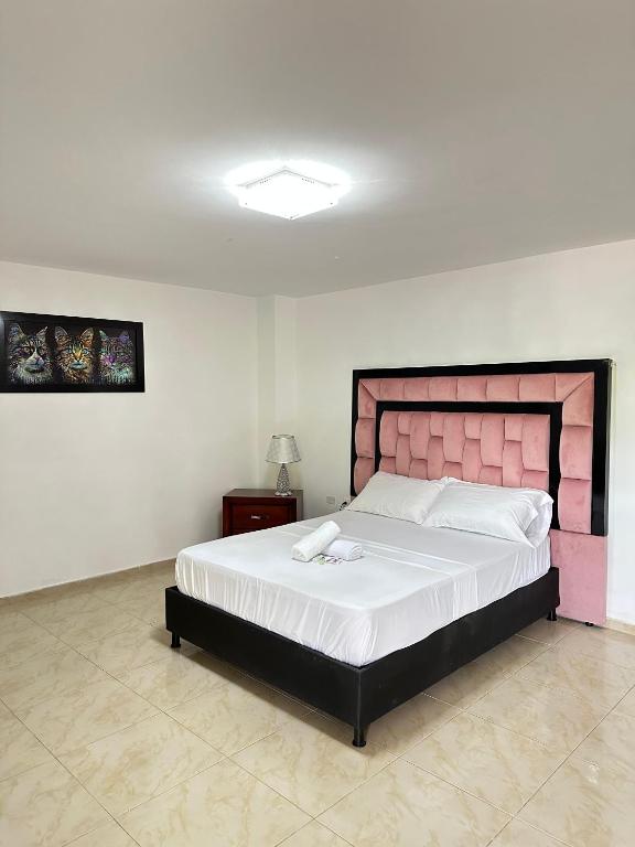 a bedroom with a large bed with a pink headboard at San Alejo in Tuluá